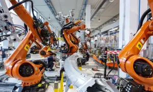 Pomarańczowe ramiona robotów KUKA pracują w fabryce, tworząc przyszłość. To zaawansowana robota automatyka.