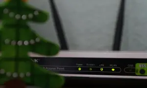 Świąteczna choinka obok routera, gotowa do konfiguracji sieci LAN. Wskaźniki Power, System, LAN, WLAN świecą się zielono.