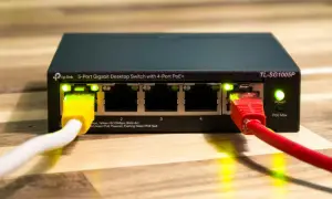 Zarządzalny switch TP-Link TL-SG1005P z 5 portami Gigabit Ethernet i 4 portami PoE+. Podłączone kable sieciowe, świecące diody LED.