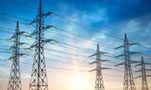 Wieże energetyczne na tle zachodzącego słońca, symbolizujące maksymalne napięcie w sieci.