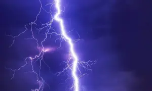Potężne wyładowanie, przepięcie prądu rozświetla nocne niebo. Błyskawice rozchodzą się niczym gałęzie drzewa.
