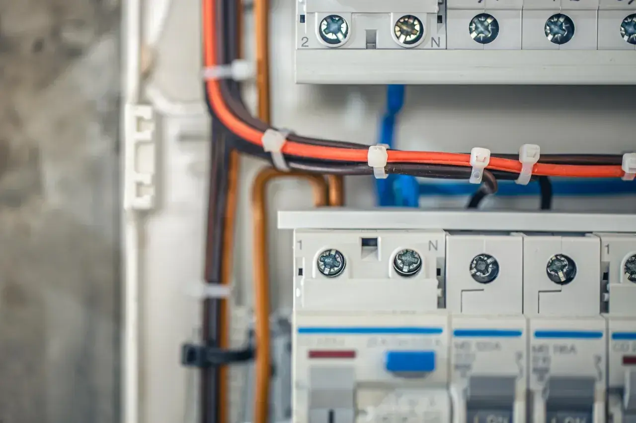 Szczegółowy widok podłączenia rozdzielnicy elektrycznej. Widać kable, bezpieczniki i zaciski.